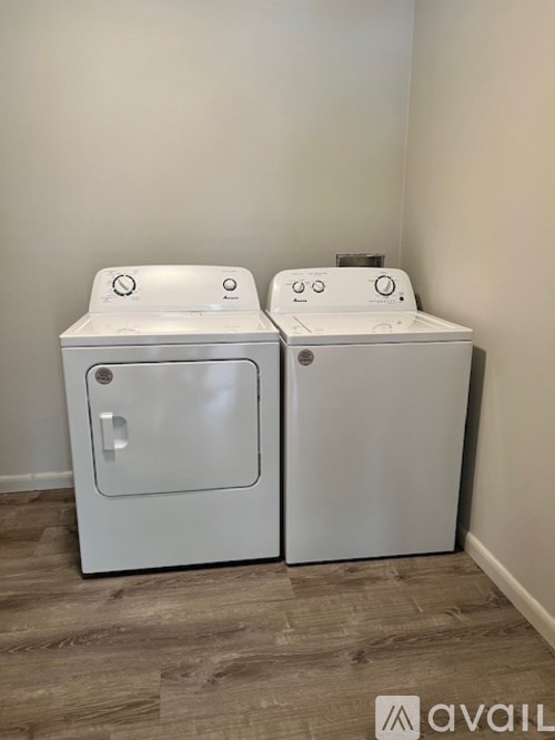 Two white washing machines in a room with wooden flooring.
