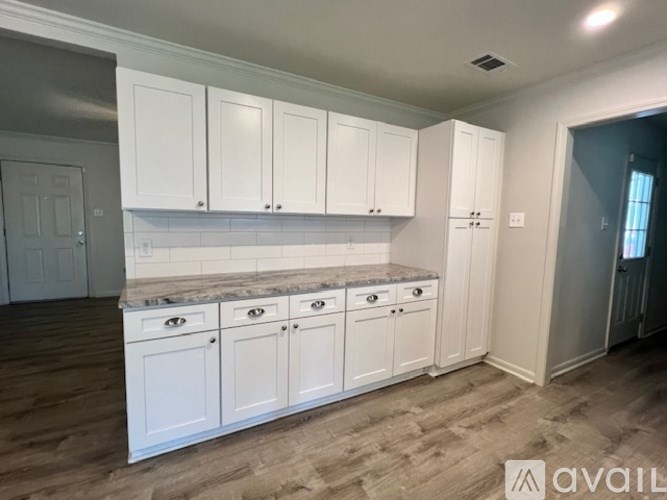 A kitchen with white cabinets and a granite countertop.
