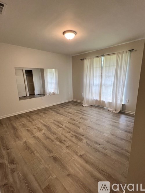 A room with wooden flooring and a window with curtains.