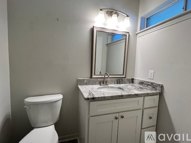 A bathroom with a toilet, sink, and mirror.