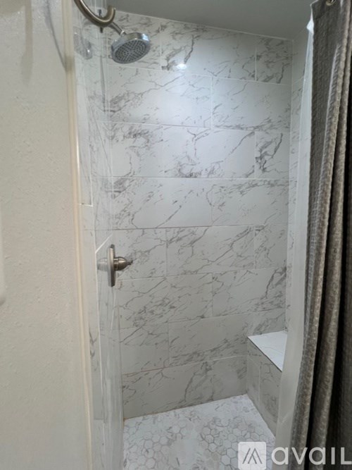A bathroom with a marble tile shower and a shower head.