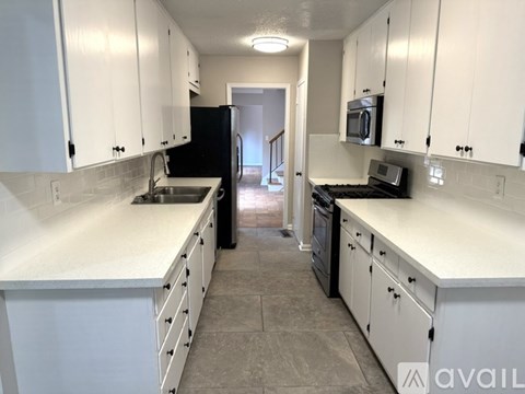 A kitchen with white cabinets and a black refrigerator.