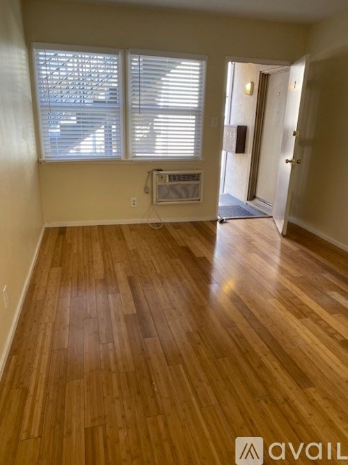 A room with wooden flooring and a window with blinds.