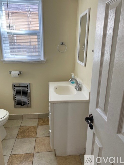 A bathroom with a toilet, sink, and window.