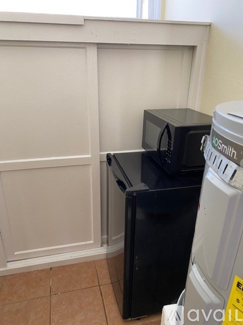 A white fridge and a black microwave in a kitchen.