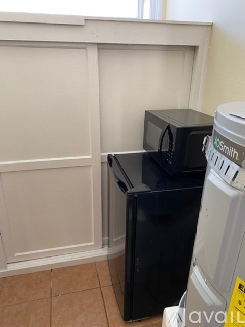 A white fridge and a black microwave in a kitchen.