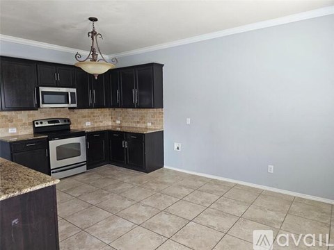 A kitchen with black cabinets and a granite counter.