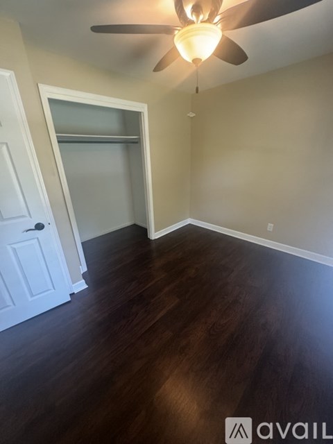 A room with a ceiling fan and wooden floors.