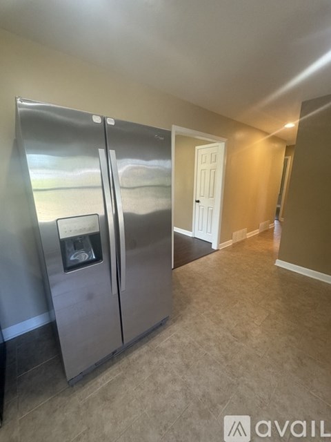 A stainless steel refrigerator with a water dispenser in the middle of the door.