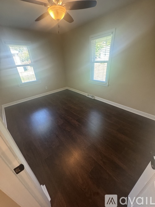 A room with a ceiling fan and two windows.