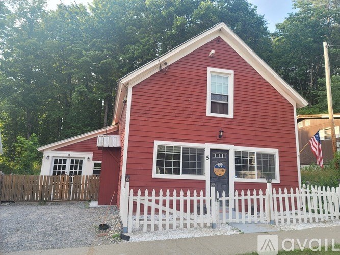 A red barn with a white picket fence in front.