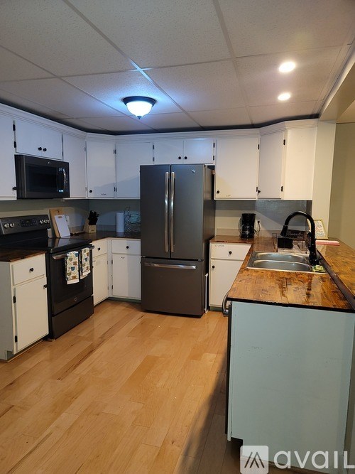 A kitchen with a refrigerator, sink, and cabinets.
