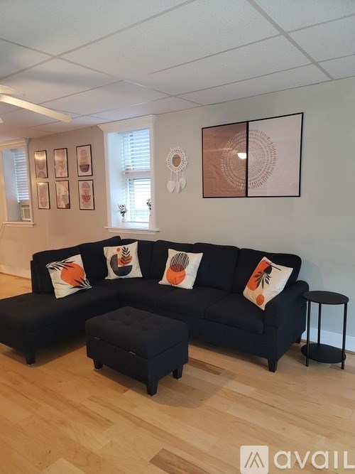 A black couch with a small ottoman in front of it.