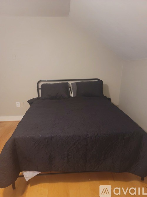 A bed with a black comforter and two pillows.
