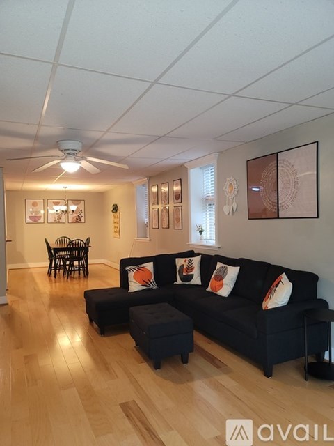 A living room with a black couch and wooden floors.