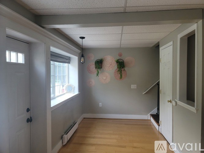A room with a wooden floor and a wall with a hanging decoration.