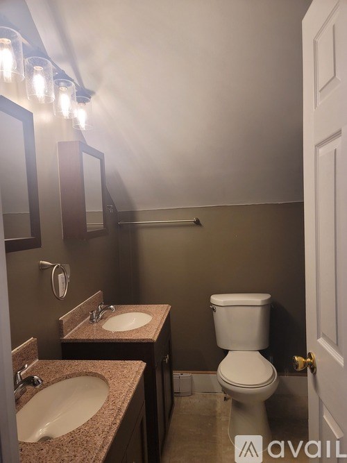 A bathroom with a toilet, two sinks and a mirror.