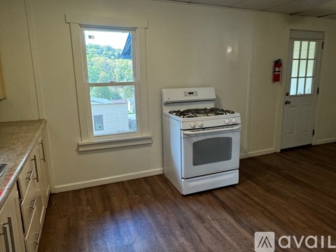 A white stove in a kitchen with wooden floors and a window.
