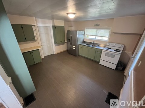 A kitchen with green cabinets and a white stove top oven.