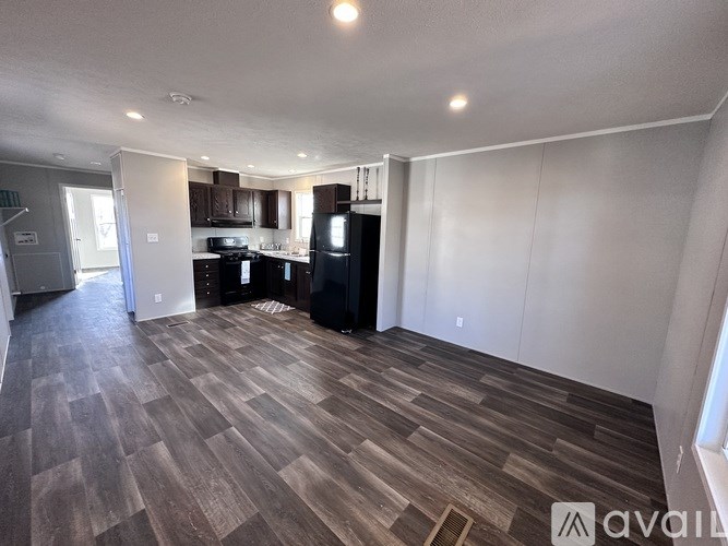 A spacious kitchen with dark wood flooring and white walls.