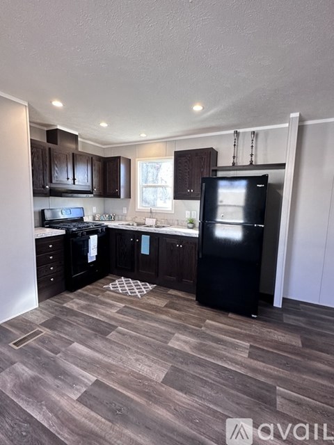 A kitchen with black cabinets and a black fridge.