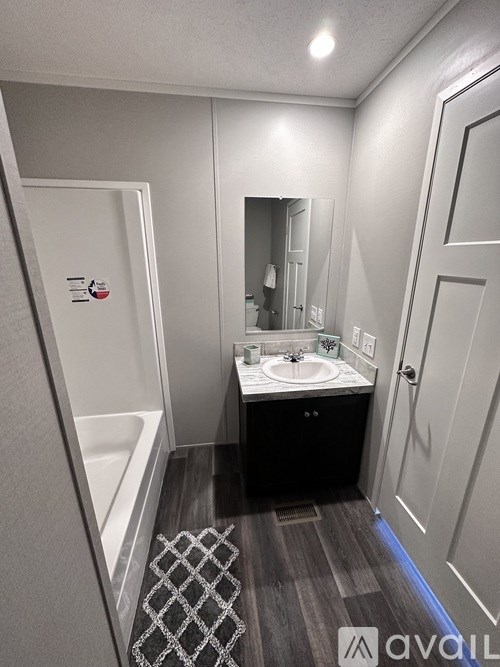 A bathroom with a sink, mirror, and bathtub.