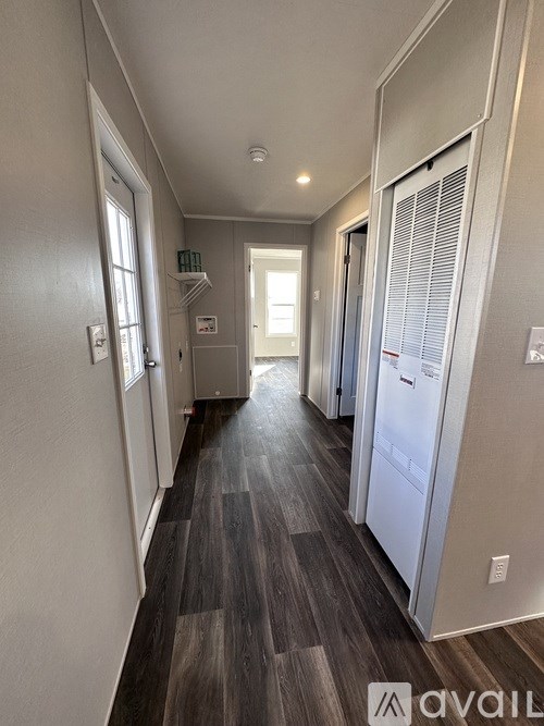 A long hallway with a refrigerator on the right side.
