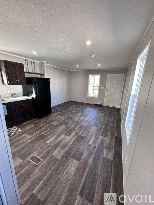 A kitchen with a black fridge and wooden flooring.