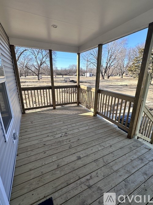 A wooden deck with a railing and a view of a field.