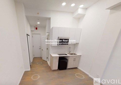 A kitchen area with a sink and cabinets in a white room.