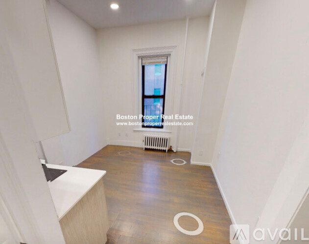 A room with wooden flooring and a window with a view of a city.