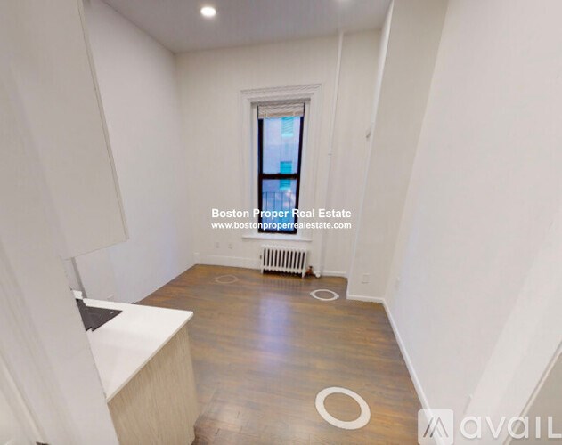 A room with wooden flooring and a window with a view of a city.