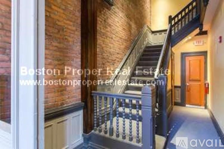A staircase with a black railing leads to a door in a building.