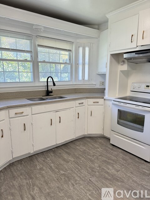A kitchen with white cabinets and a grey floor.