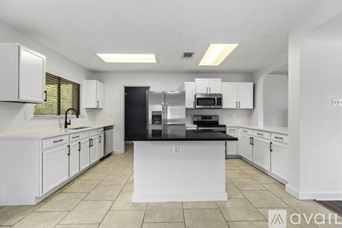 A kitchen with white cabinets and a black countertop.