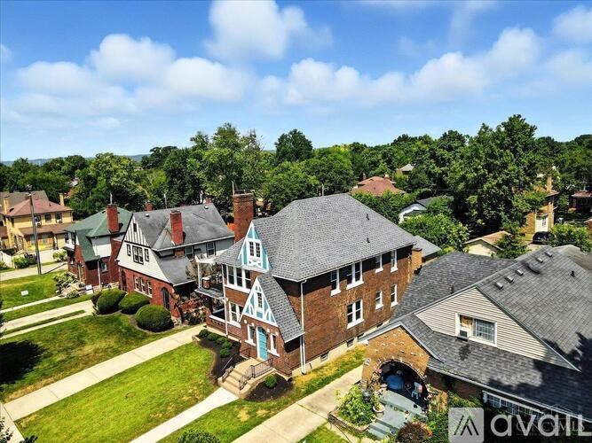 A large brick house with a blue door and a tree in front.