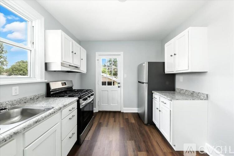 A kitchen with white cabinets and a wooden floor.