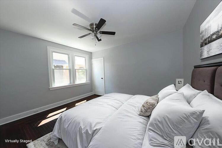 A bedroom with a bed, a ceiling fan, and two pictures on the wall.