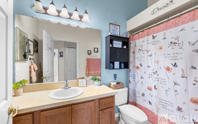 A bathroom with a sink, mirror, toilet, and a shower curtain with butterflies on it.