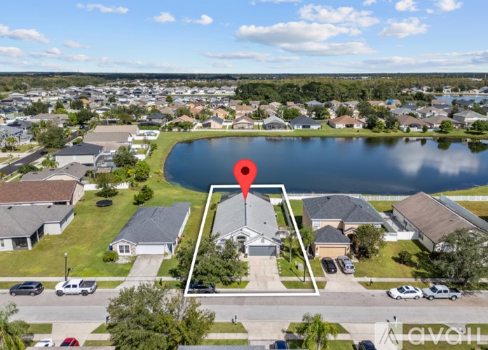 A bird's eye view of a residential area with a lake and a house with a red marker on it.