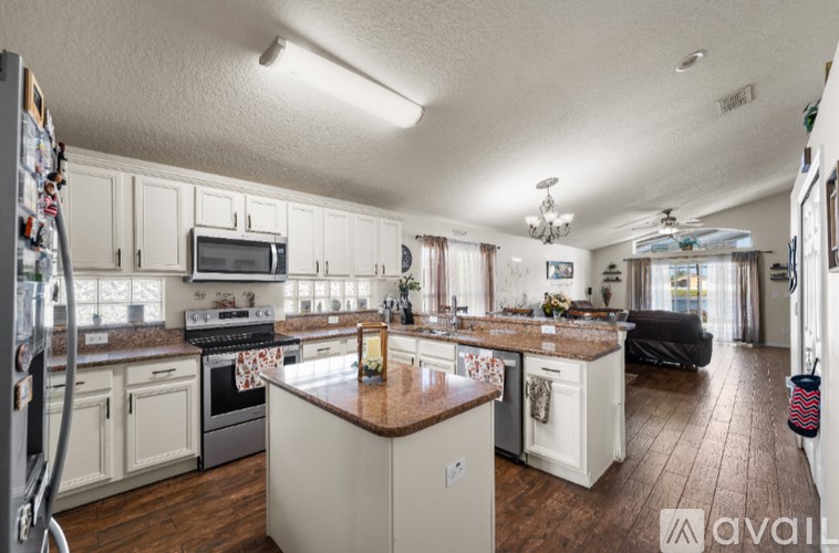 A kitchen with white cabinets and a brown island.