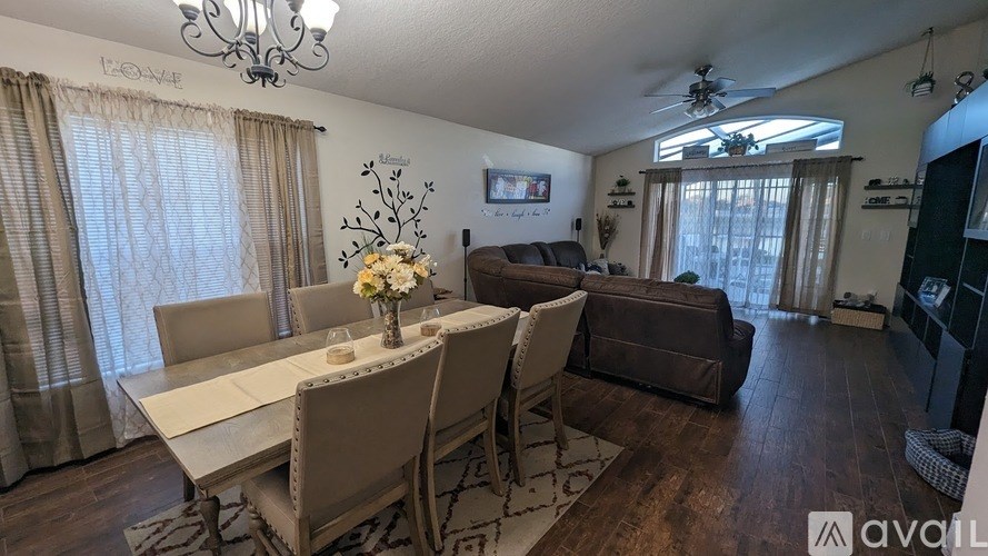 A dining room with a table set for six and a couch in the background.