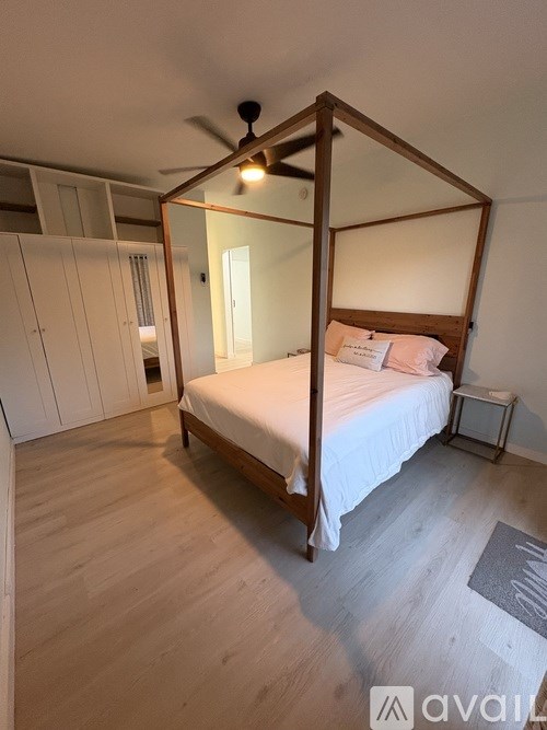 A bedroom with a four poster bed and a ceiling fan.