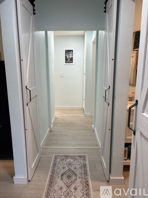 A hallway with a rug on the floor and a door on the left.