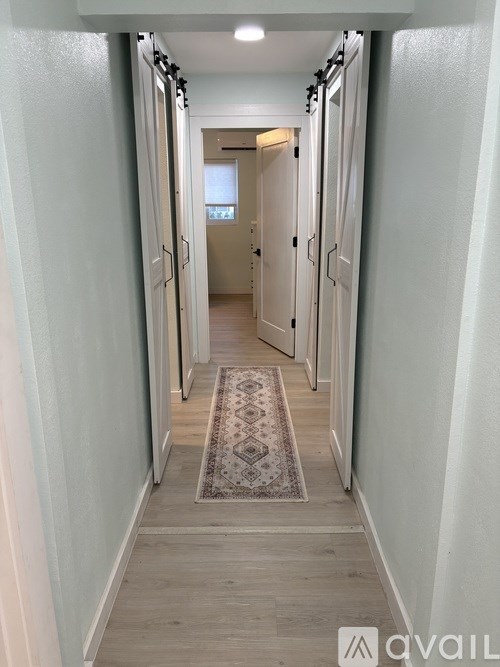 A hallway with a rug on the floor and doors on both sides.
