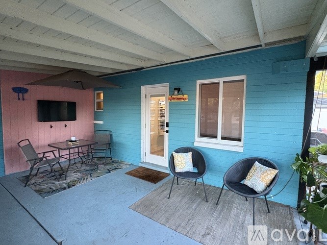 A blue house with a pink wall and a white door.