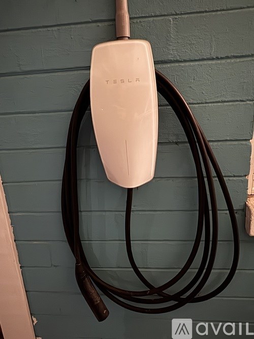 A Tesla wall charger plugged into a power outlet.