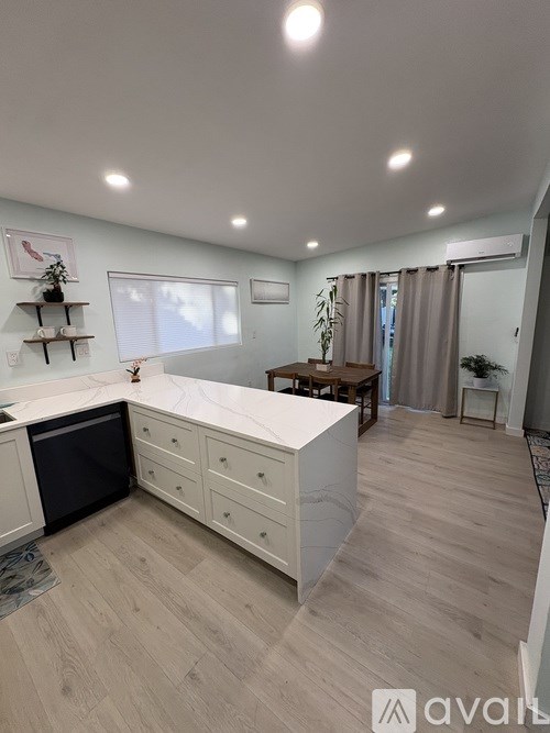 A kitchen with a white countertop and wooden flooring.