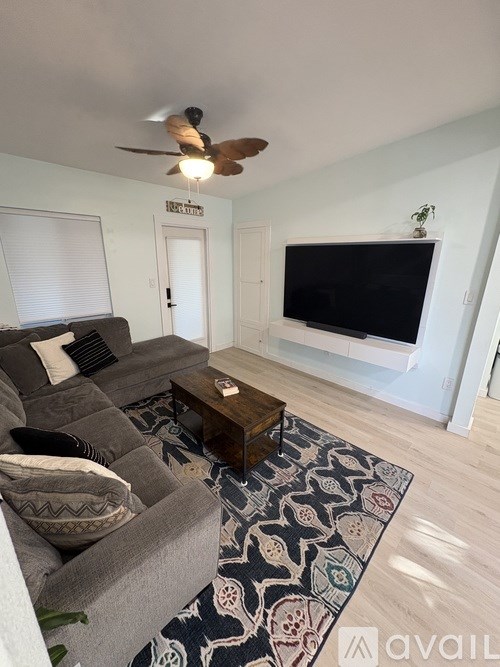 A living room with a grey couch and a black television.