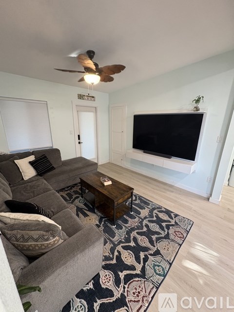 A living room with a grey couch and a black television.